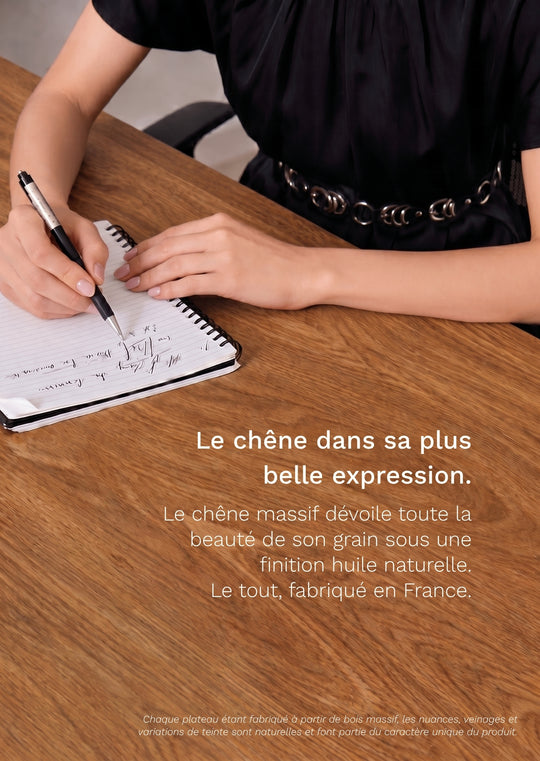 Personne écrivant sur le plateau PREMIUM OAK AUM WORLD en chêne massif Made in France, mettant en valeur le veinage du bois.